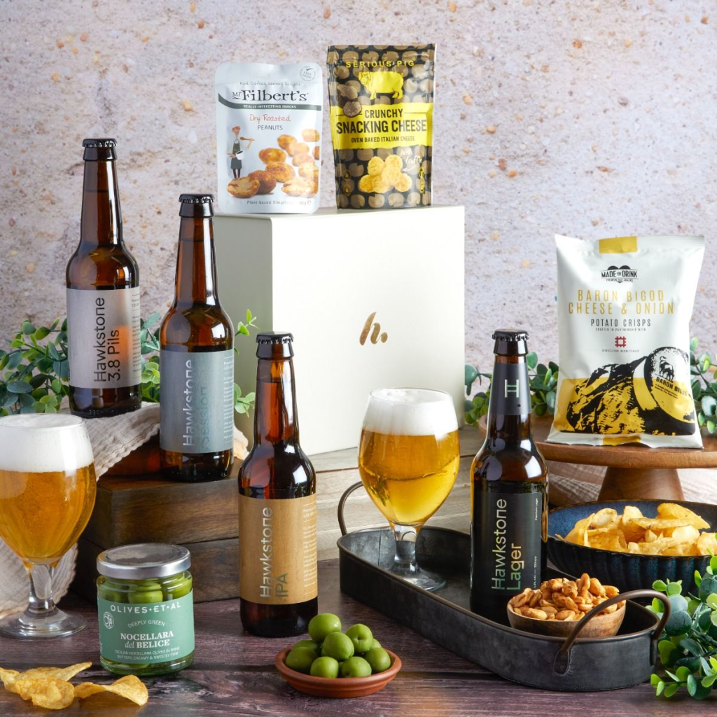 This image shows the Hawkstone Luxury Beer Hamper - a hampers.com gift with four beers and a selection of snacks.