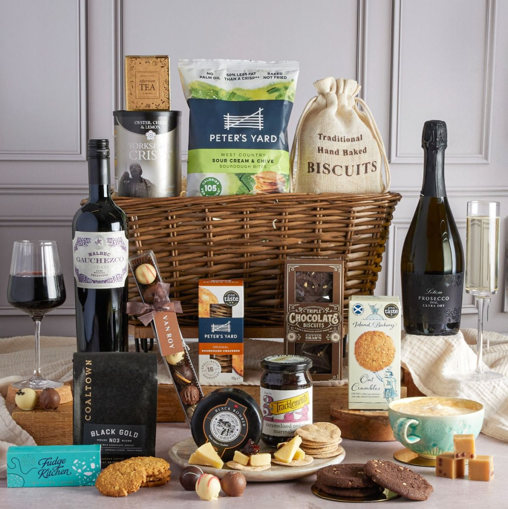 This image shows the Luxury Food & Wine Basket Hamper - a hampers.com gift hamper with two bottles of wine and a selection of snacks